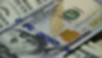 Close-up of U.S. 100-dollar bills with Benjamin Franklin's face, green Treasury seal.
