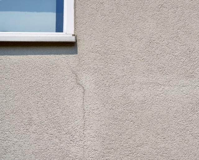 Subtle crack in stucco wall near window.