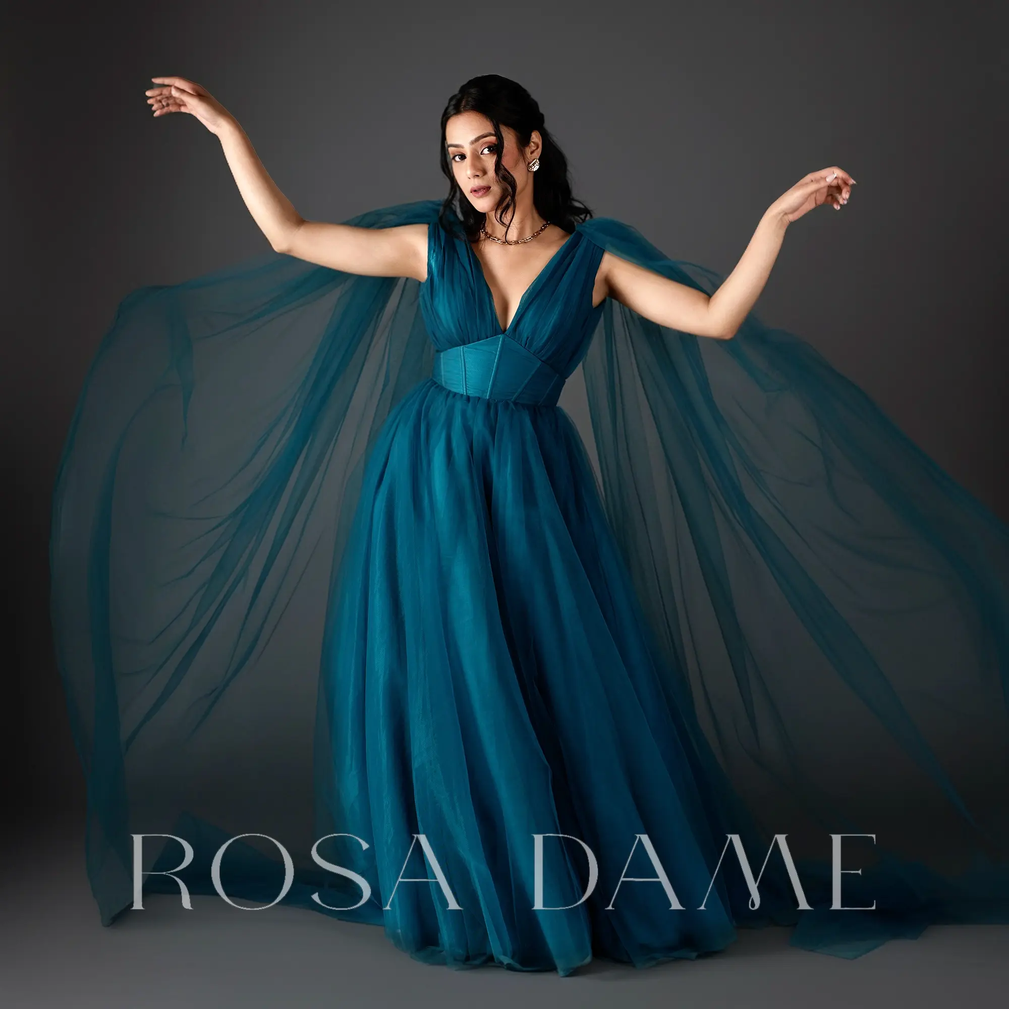 front view of teal draped tulle evening gown with deep V neckline and corset waist