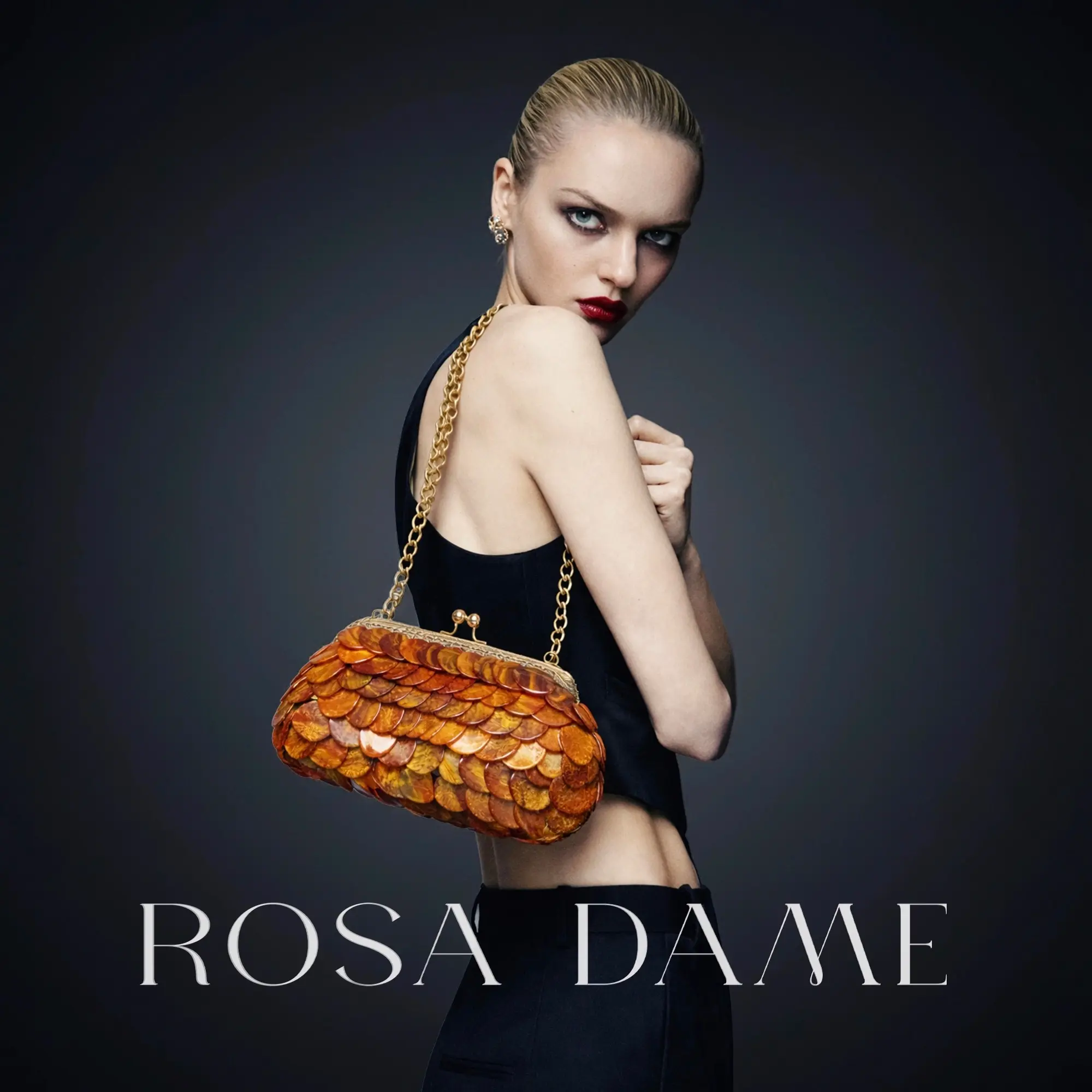 Model wearing burnt amber layered disc evening clutch with gold chain by Rosa Dame.