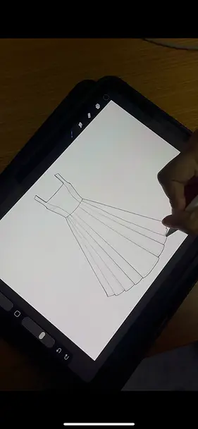 Fashion designer sketching a pleated dress design on tablet using digital stylus