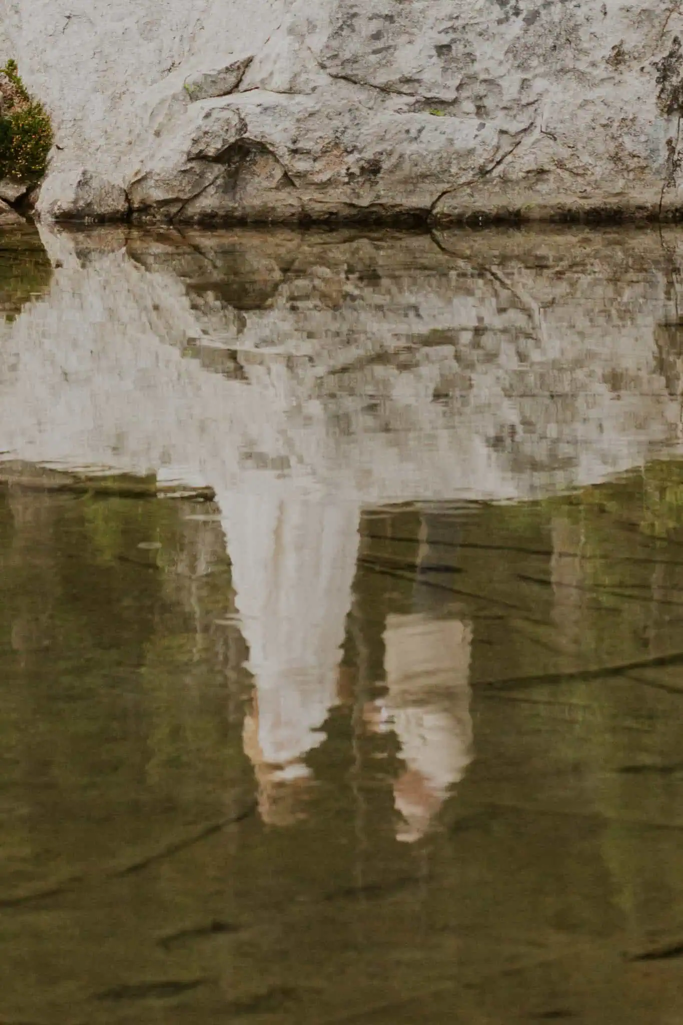 a couple reading vows on a rock in the water for their elopement