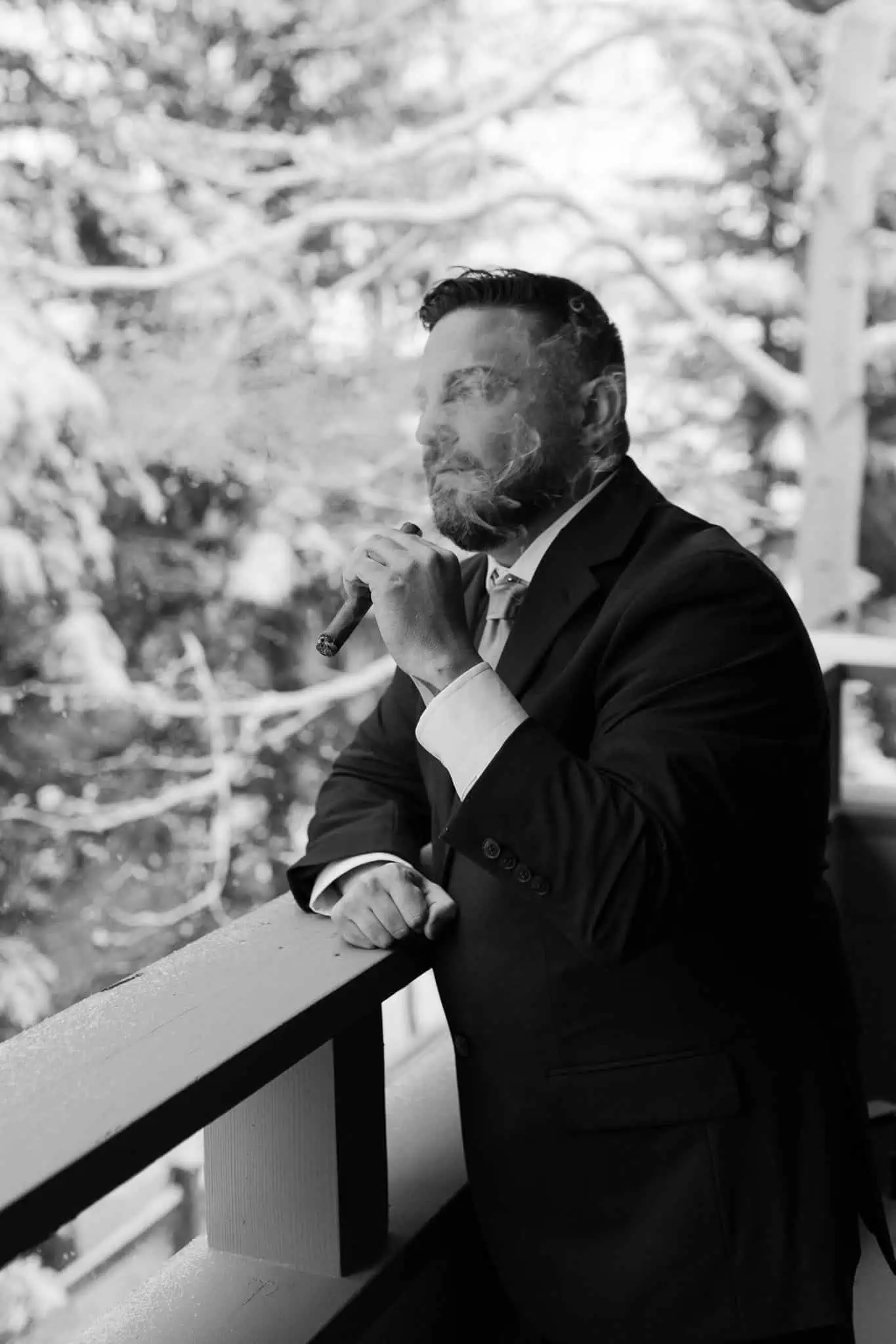 a groom smoking a cigar in the snow