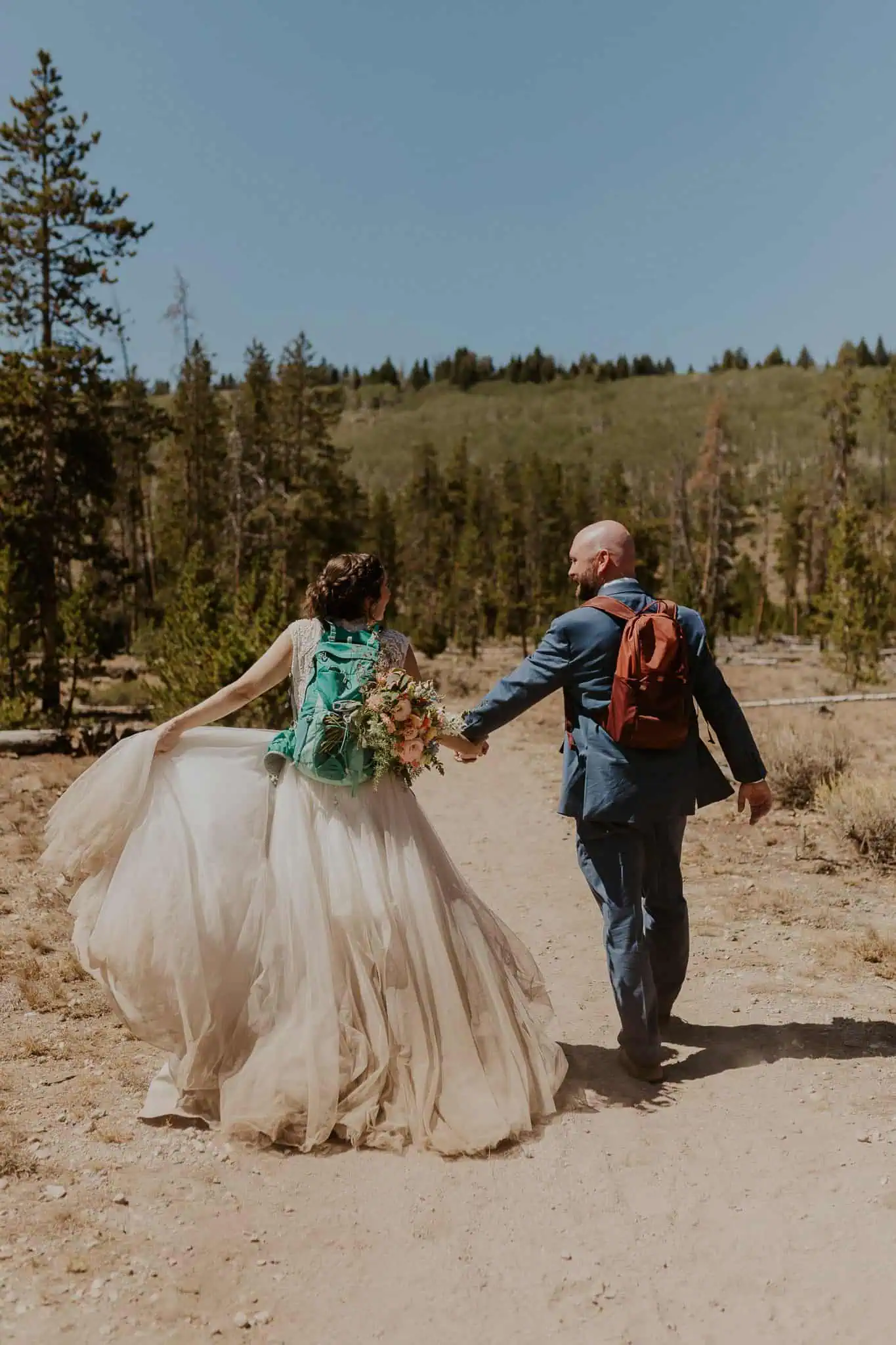 bride and groom holding hands and hiking