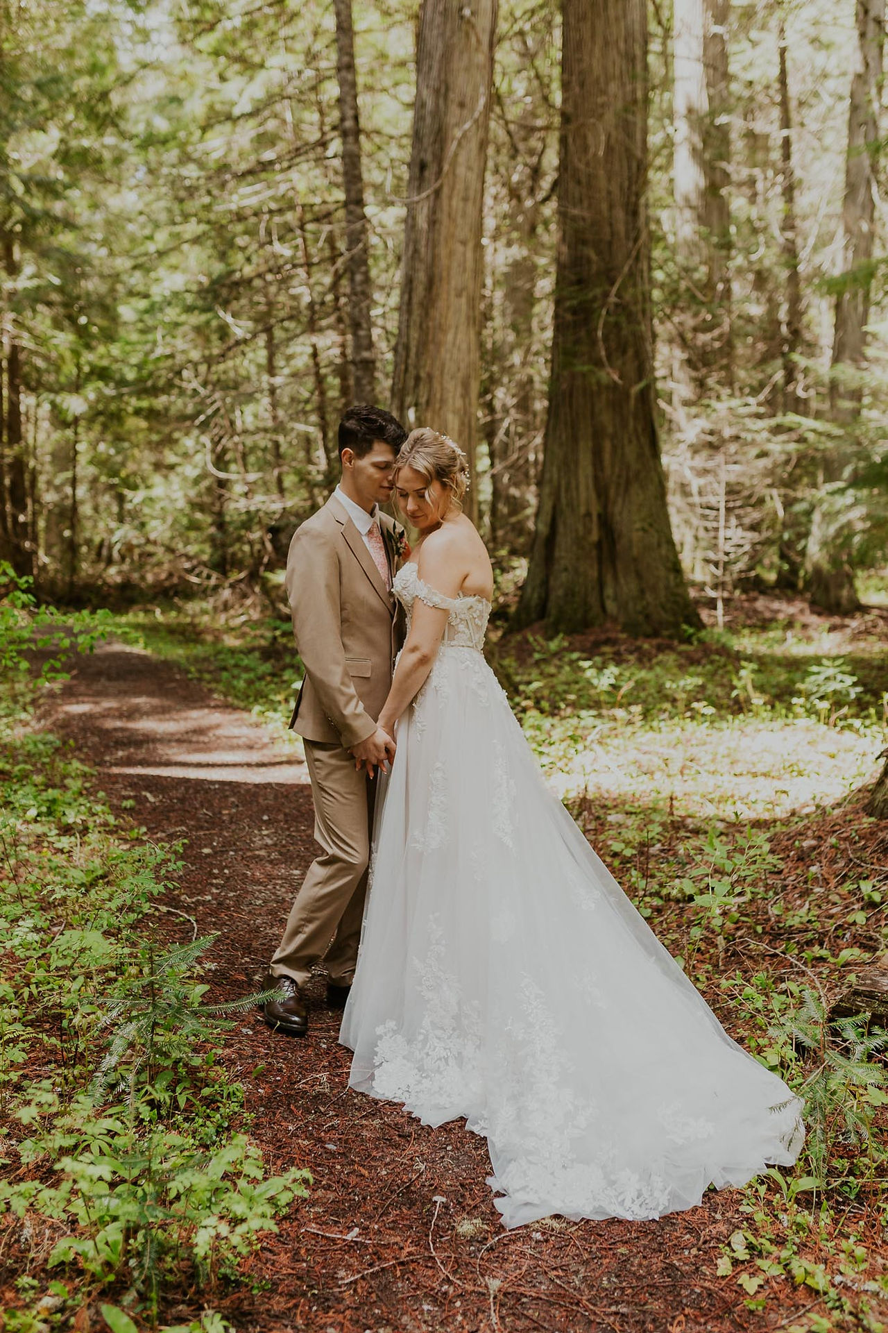 bride and groom standing with heads together on hiking trail
