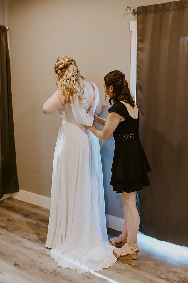 bridesmaid helping bride zip up dress
