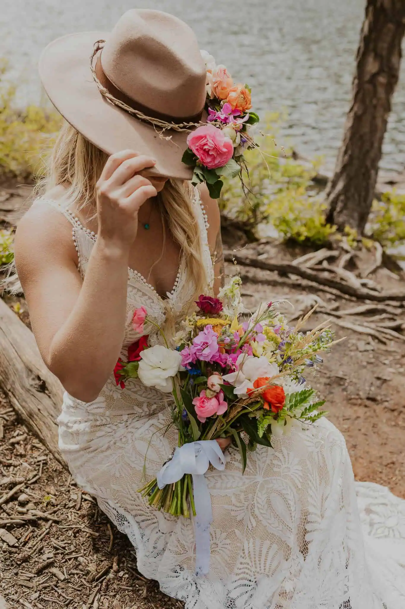 a bride sitting on a tree trunk holding her flowers