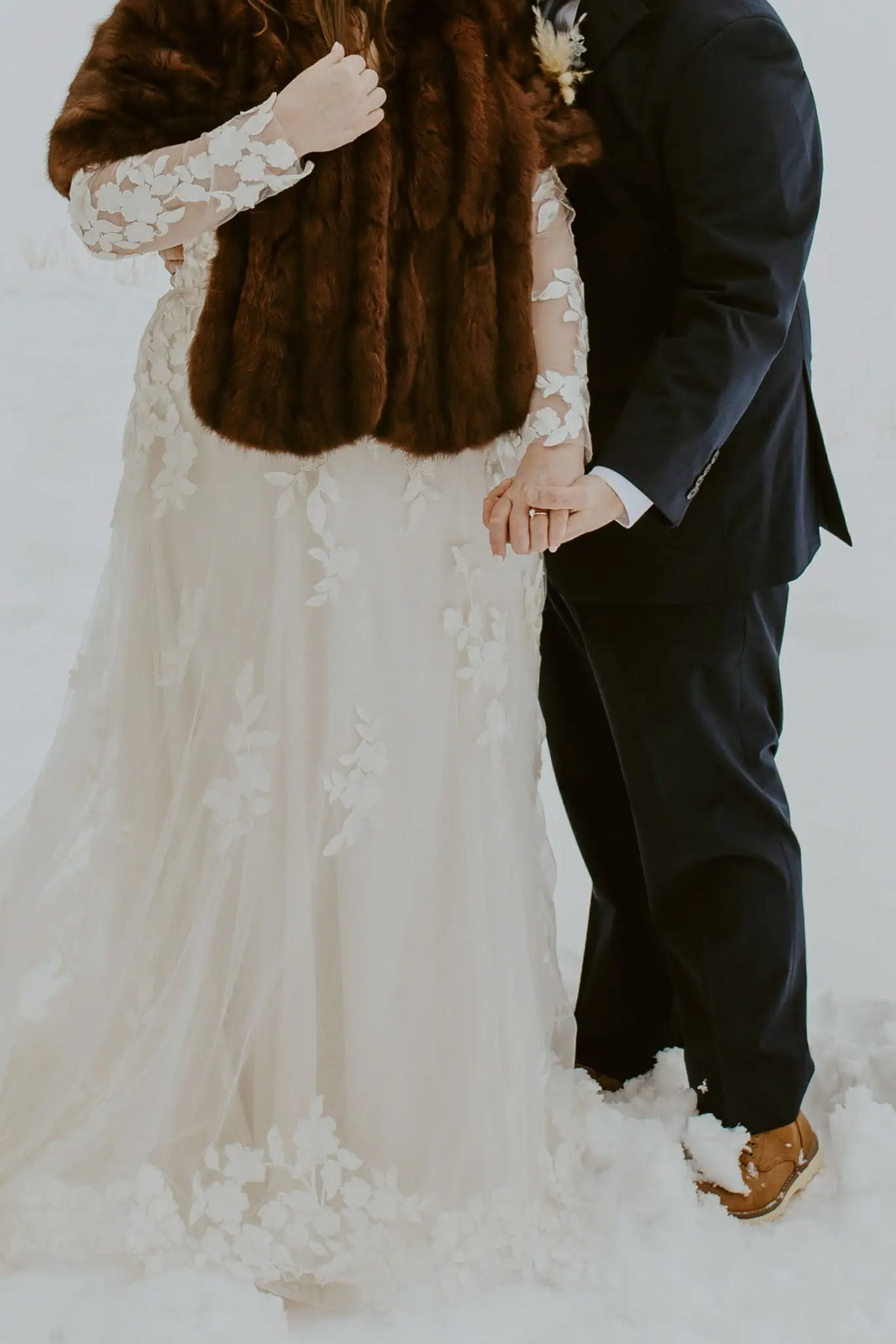 bride and groom holding hands in the snow