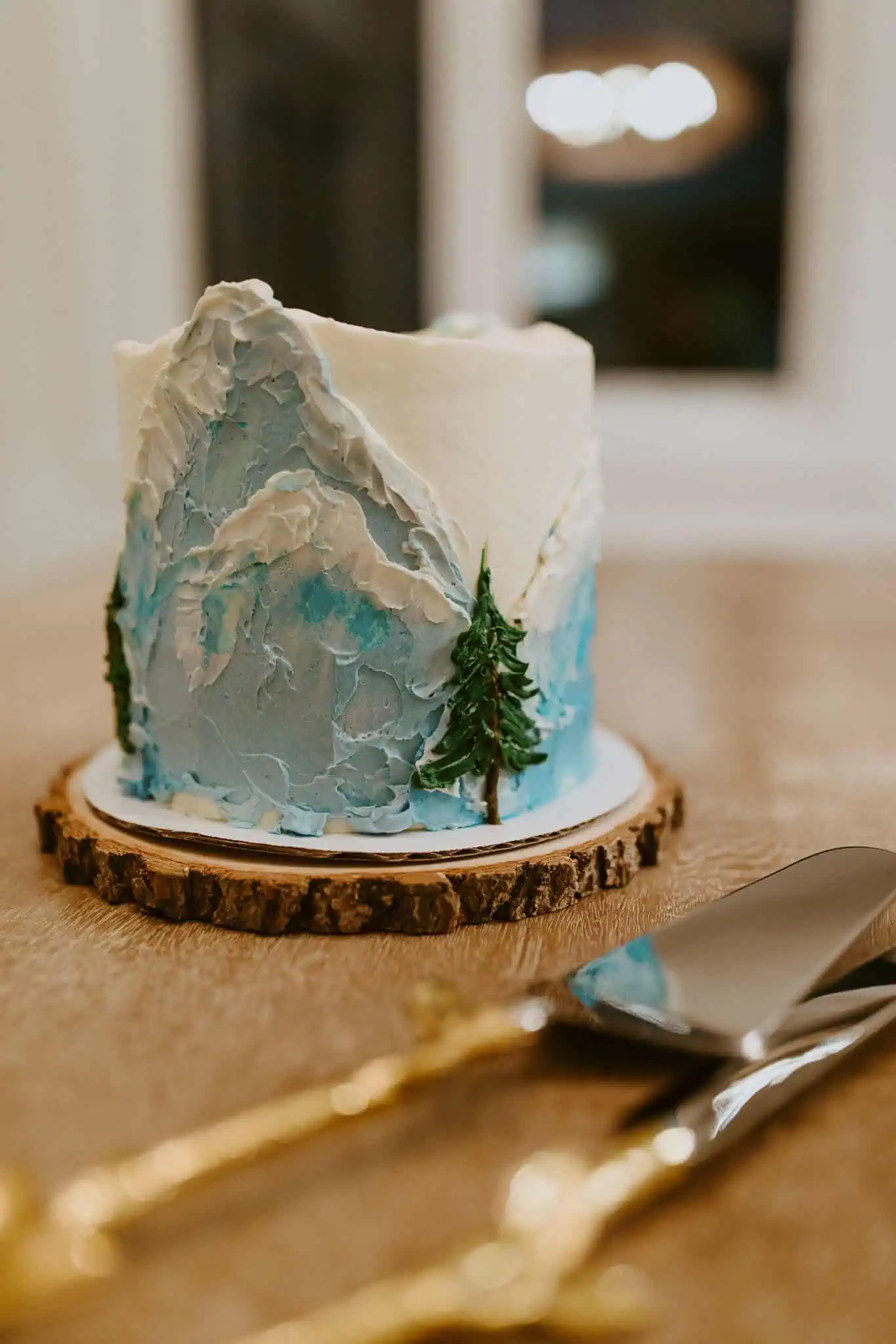 a small wedding cake with blue mountains and trees on it