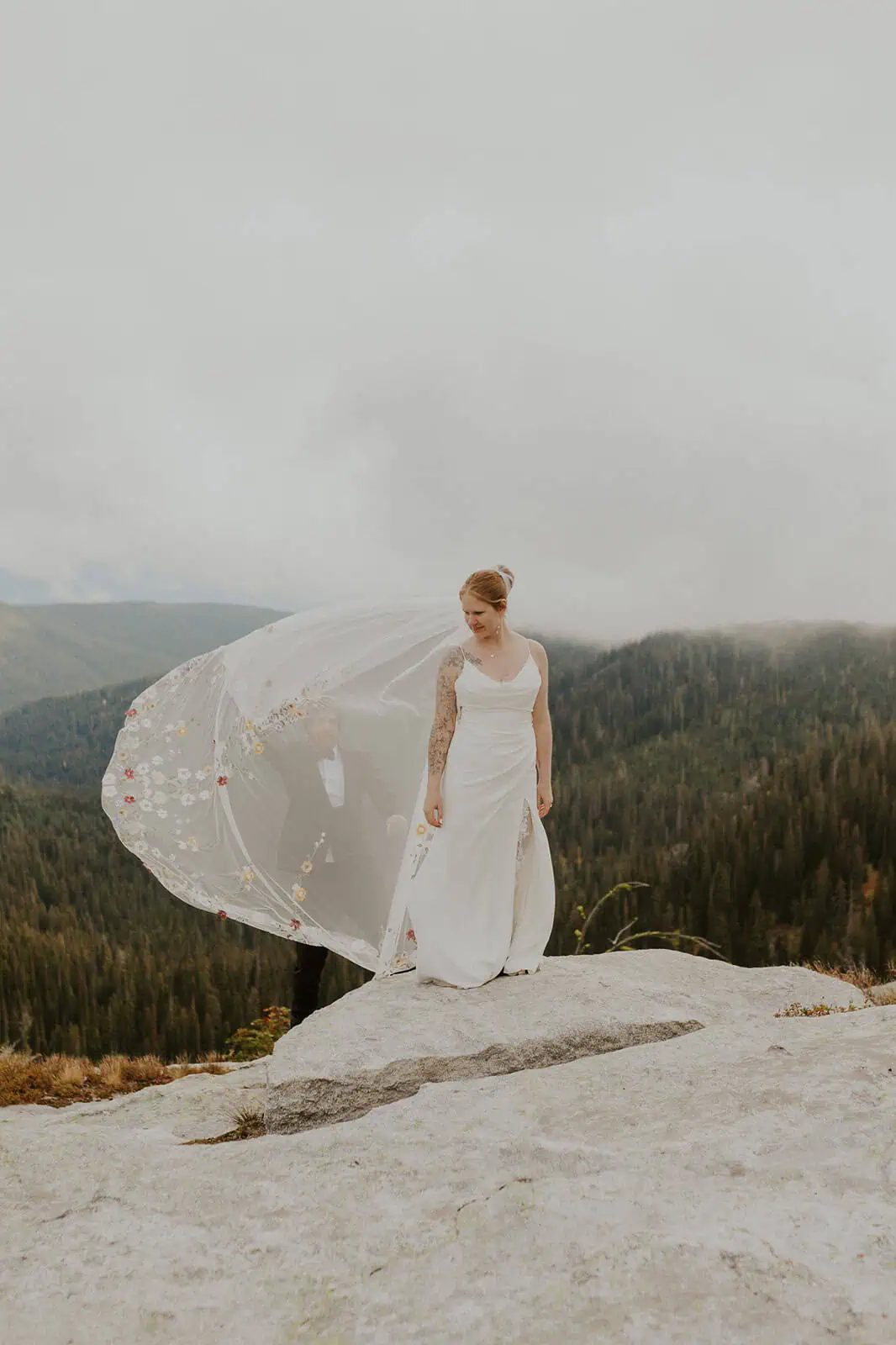 bride in mountains with veil blowing in the wind