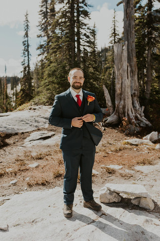 a groom putting on his jacket for his adventure elopement in the mountains