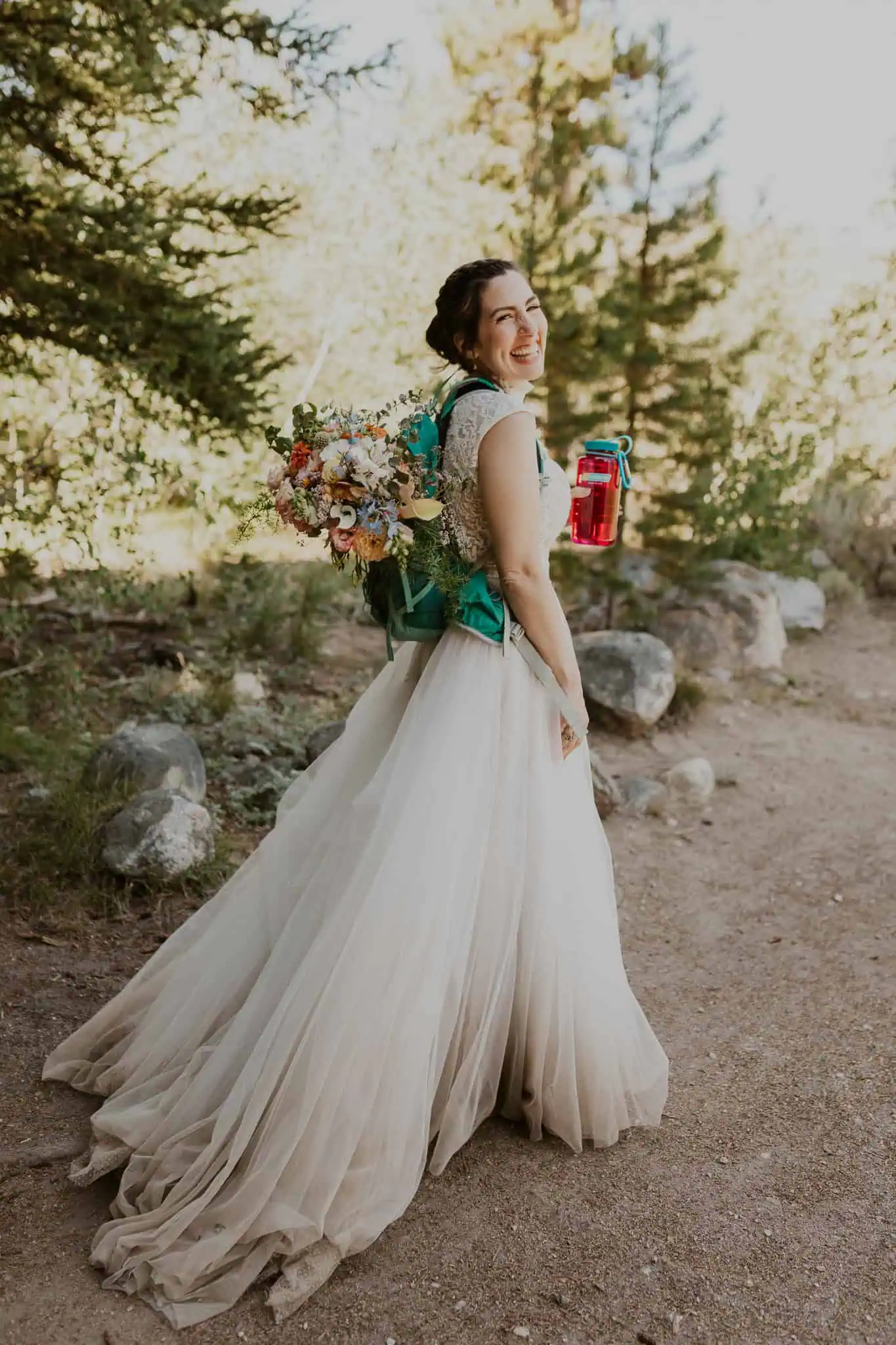 bride smiling and wearing a hiking backpack