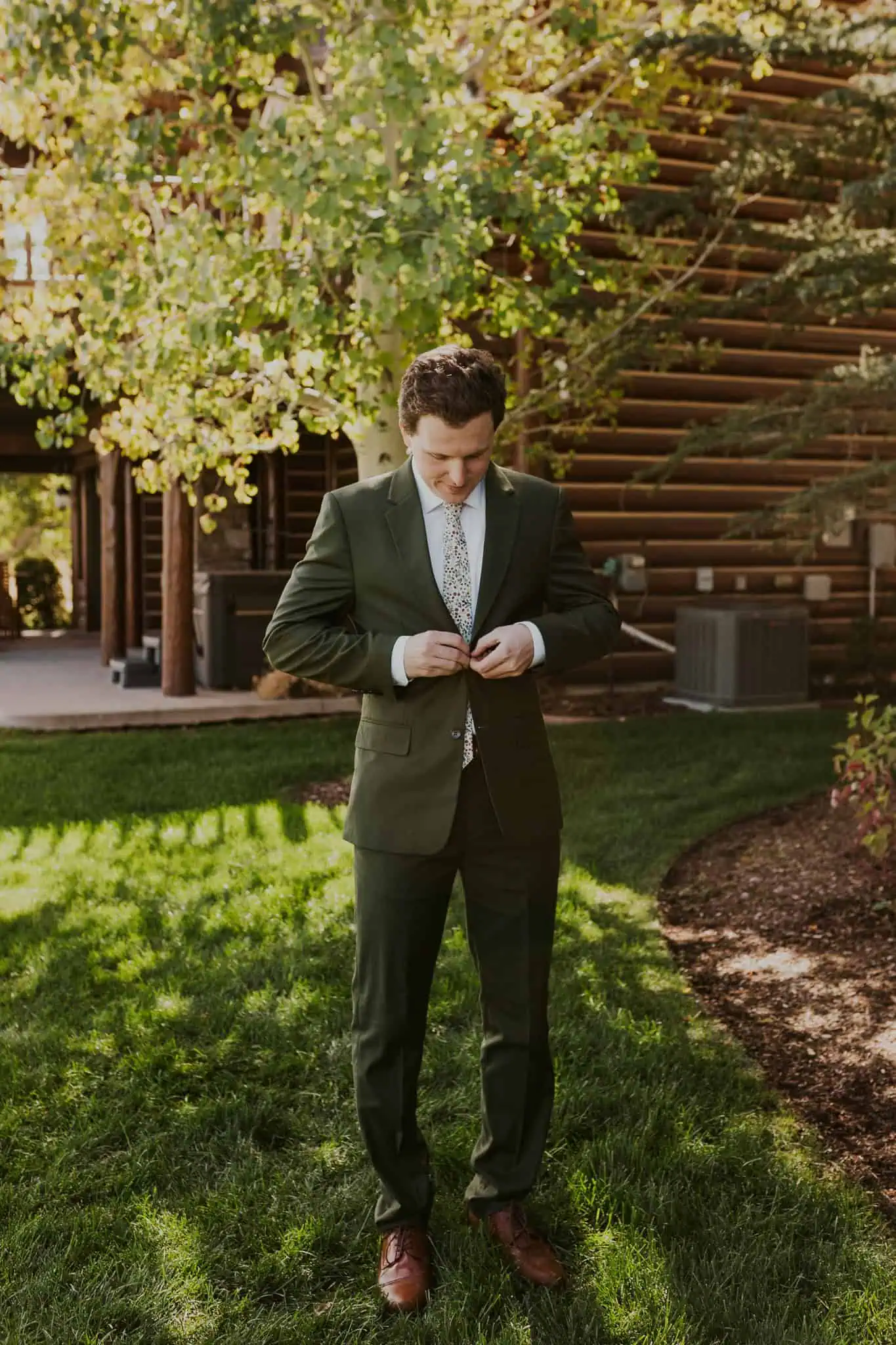 groom buttoning a green suit