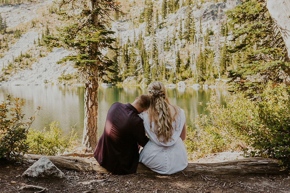 a couple sitting on a log at an alpine lake