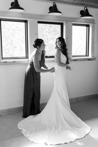mom helping bride into wedding dress