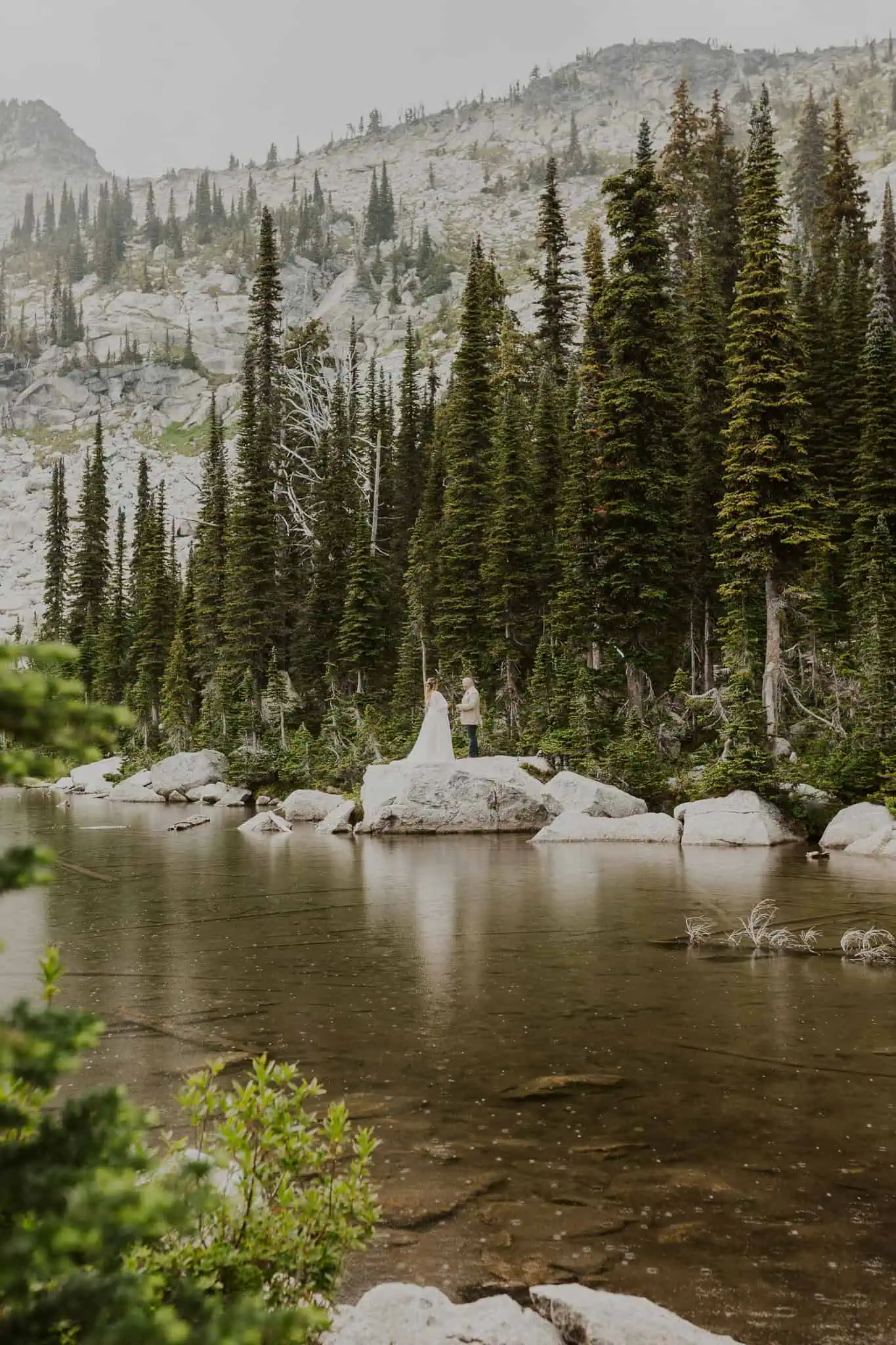a couple reading vows on a rock in the water for their elopement