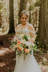 a bride holding a big flower bouquet in a forest