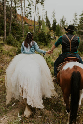 bride and groom holding hands while riding horses