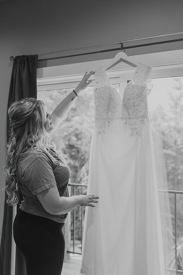 bride holding her dress on a hanger by a sliding door
