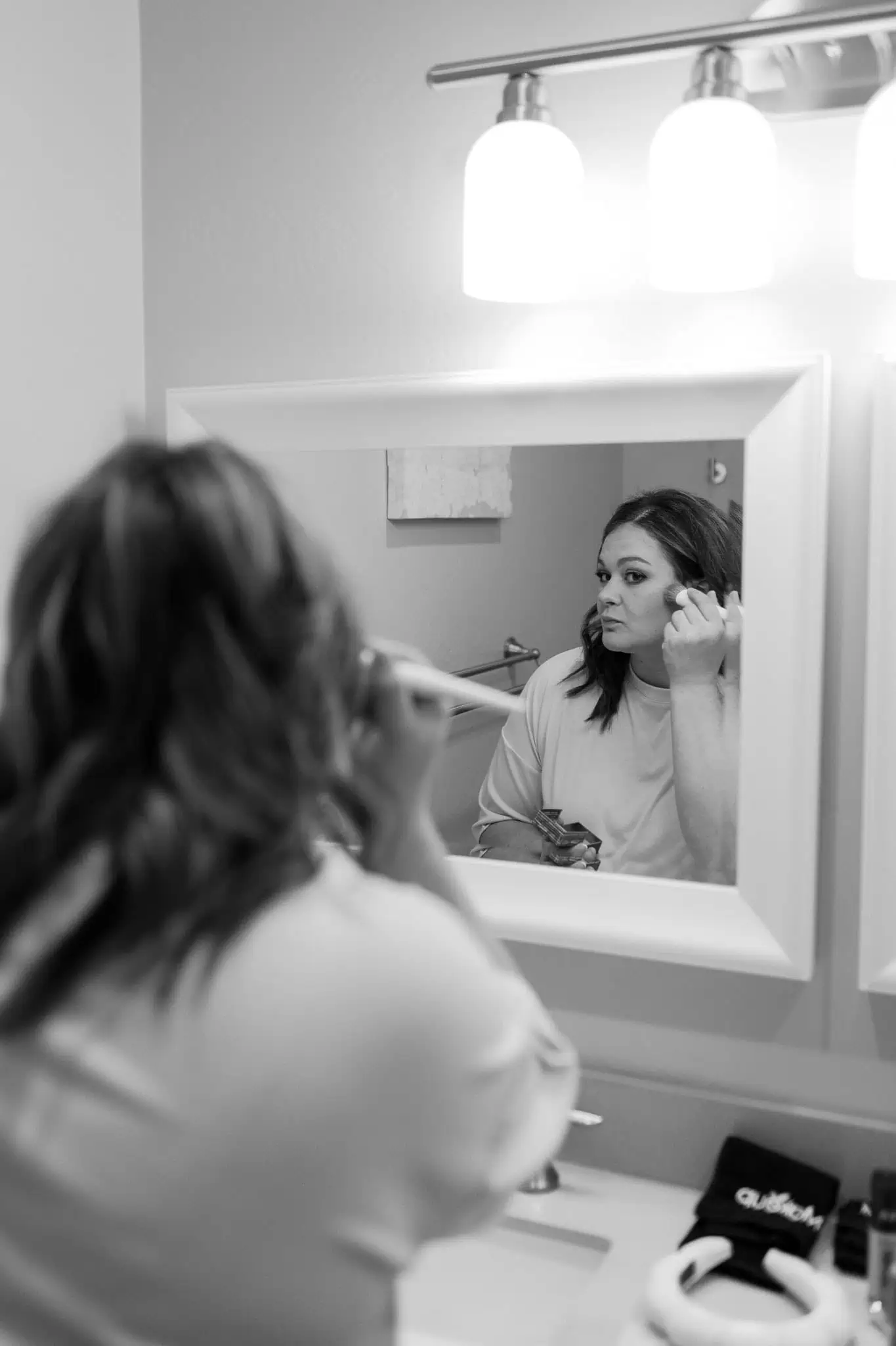 bride putting on makeup in the bathroom mirror