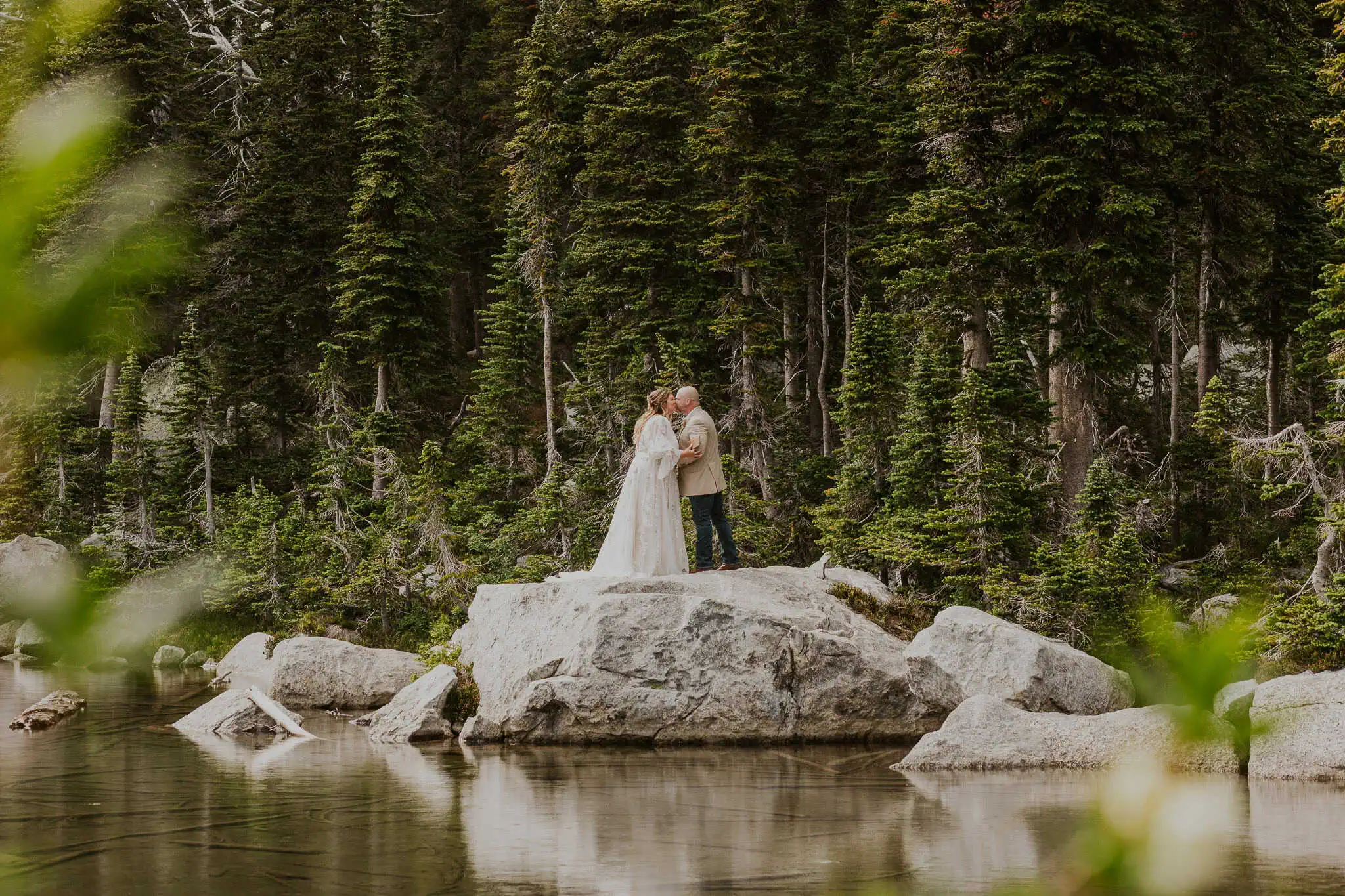 a couple reading vows on a rock in the water for their elopement
