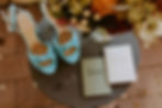 a pair of blue heels next to flowers and vow books