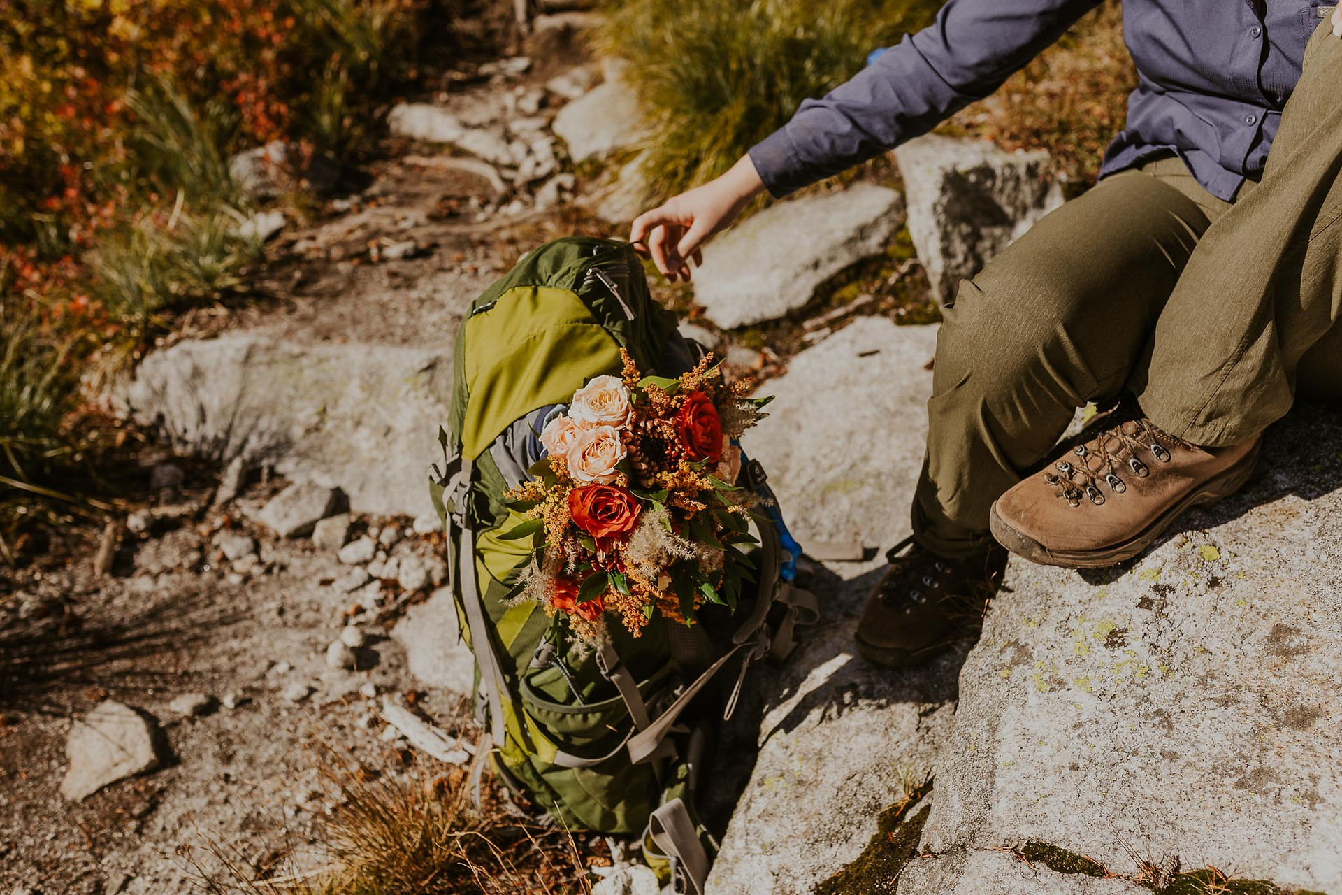 a hiker holding her pack with a flower bouquet in it