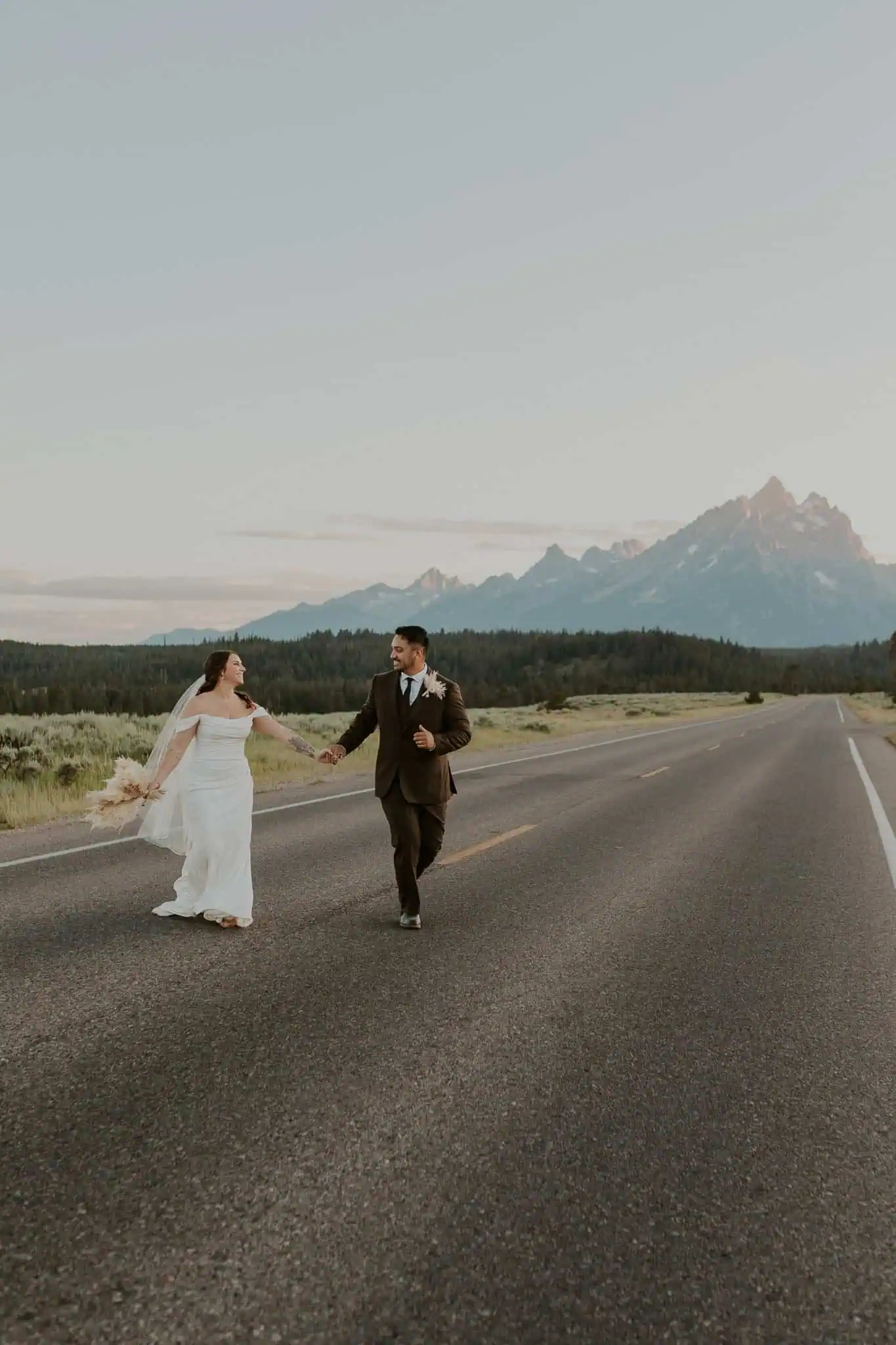 a couple running across the road in the tetons