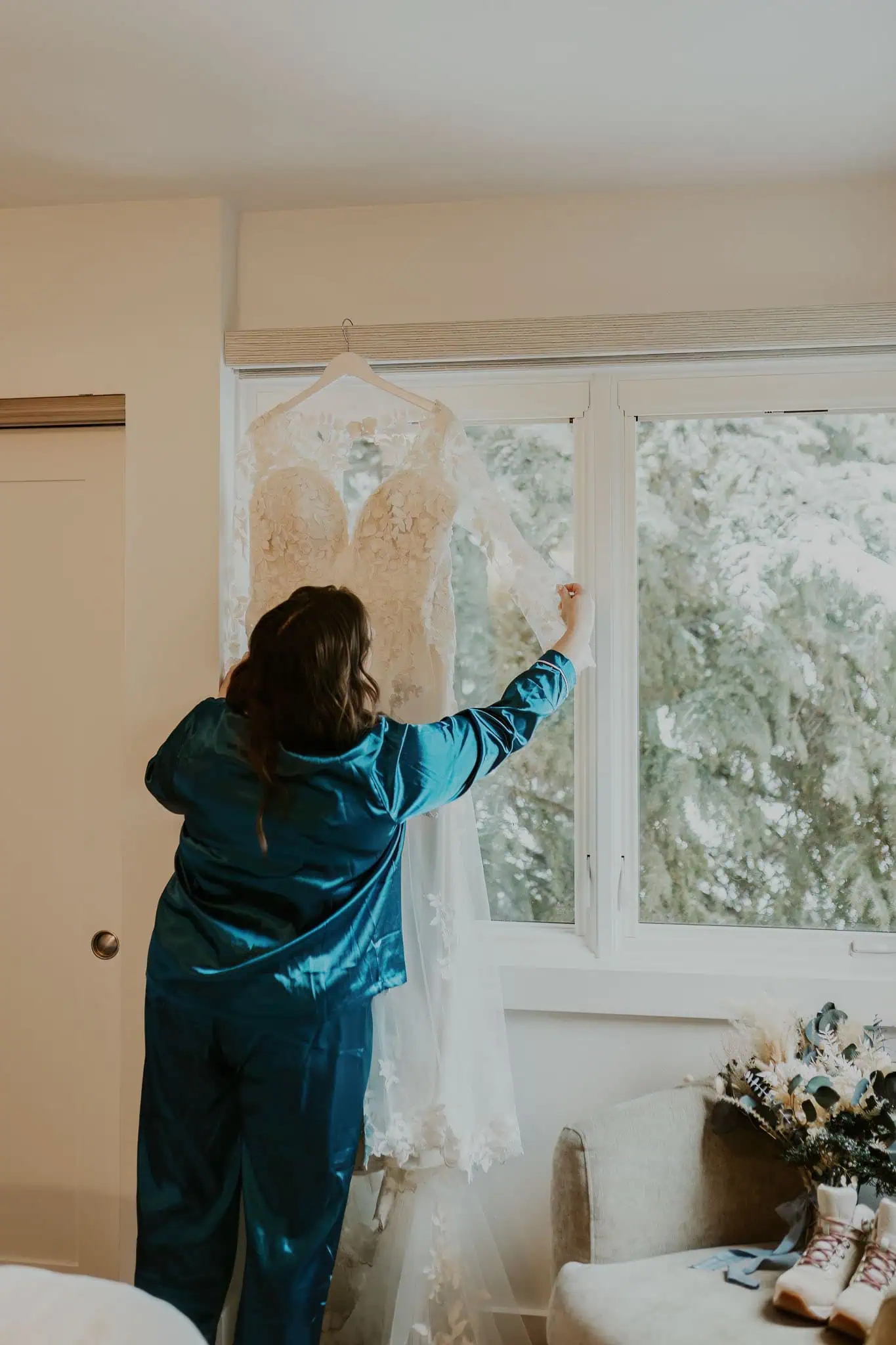 a bride hanging her dress on a window