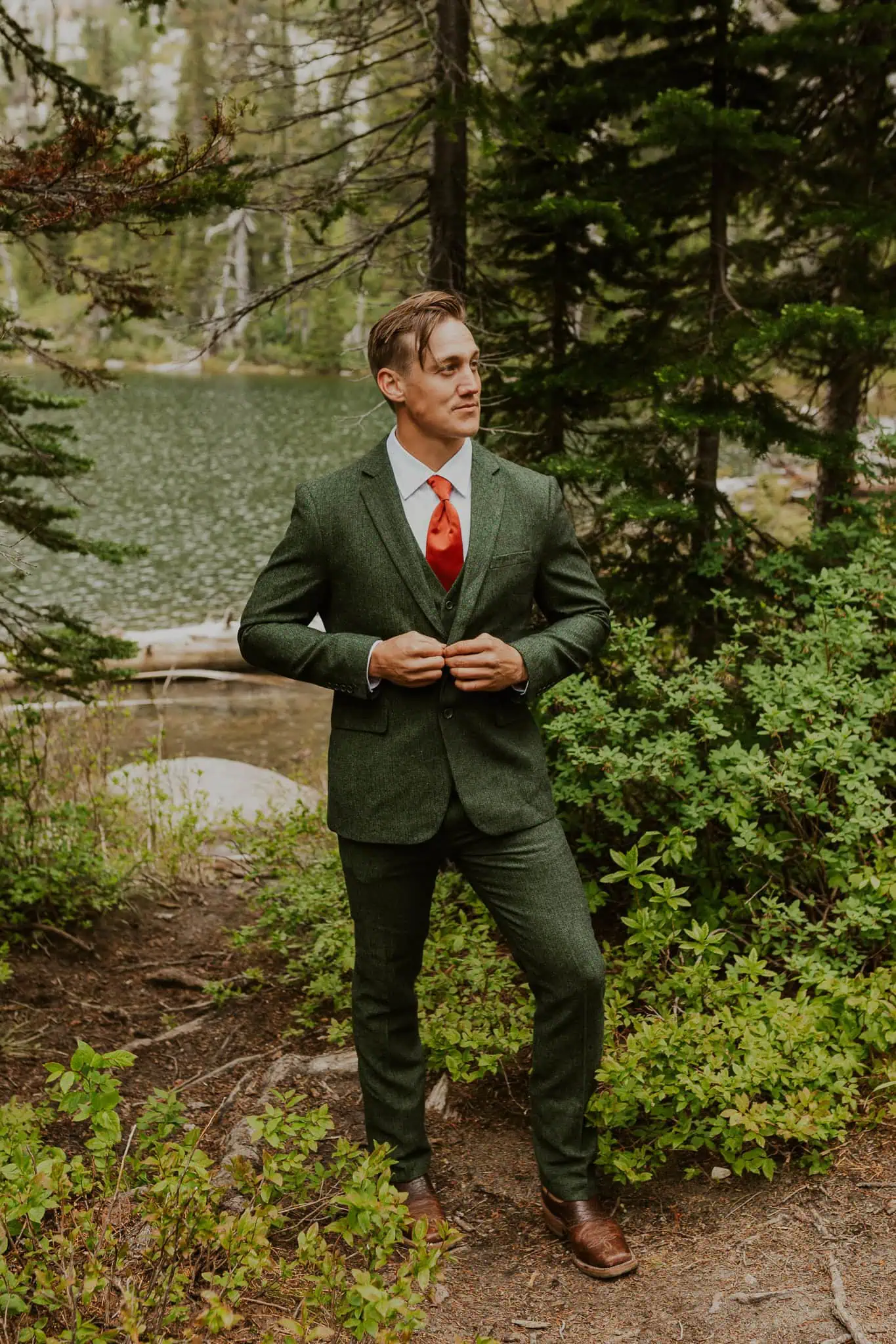 a groom buttoning up his green suit