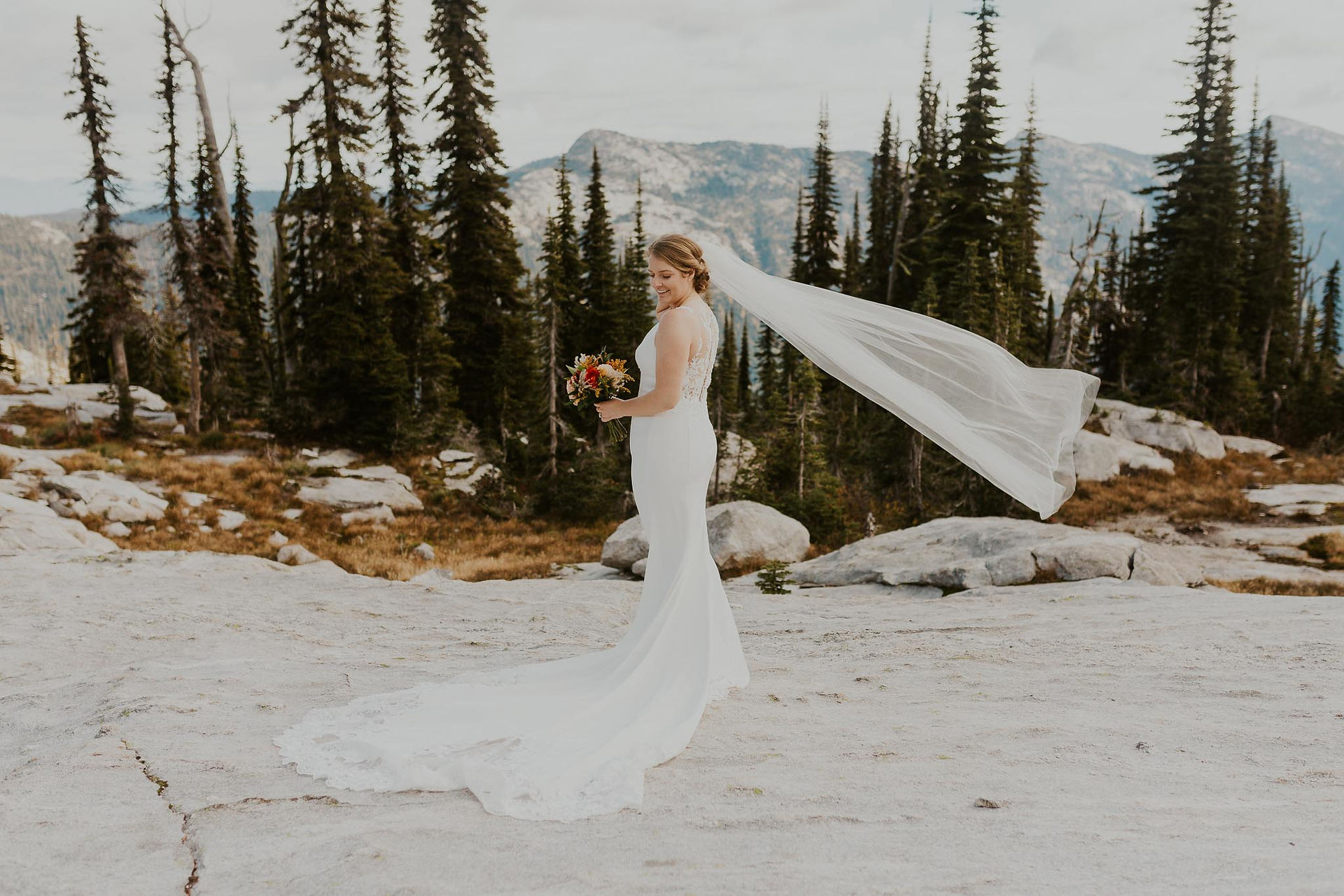 a bridal portrait of an adventure bride with her veil blowing in the wind in the mountains