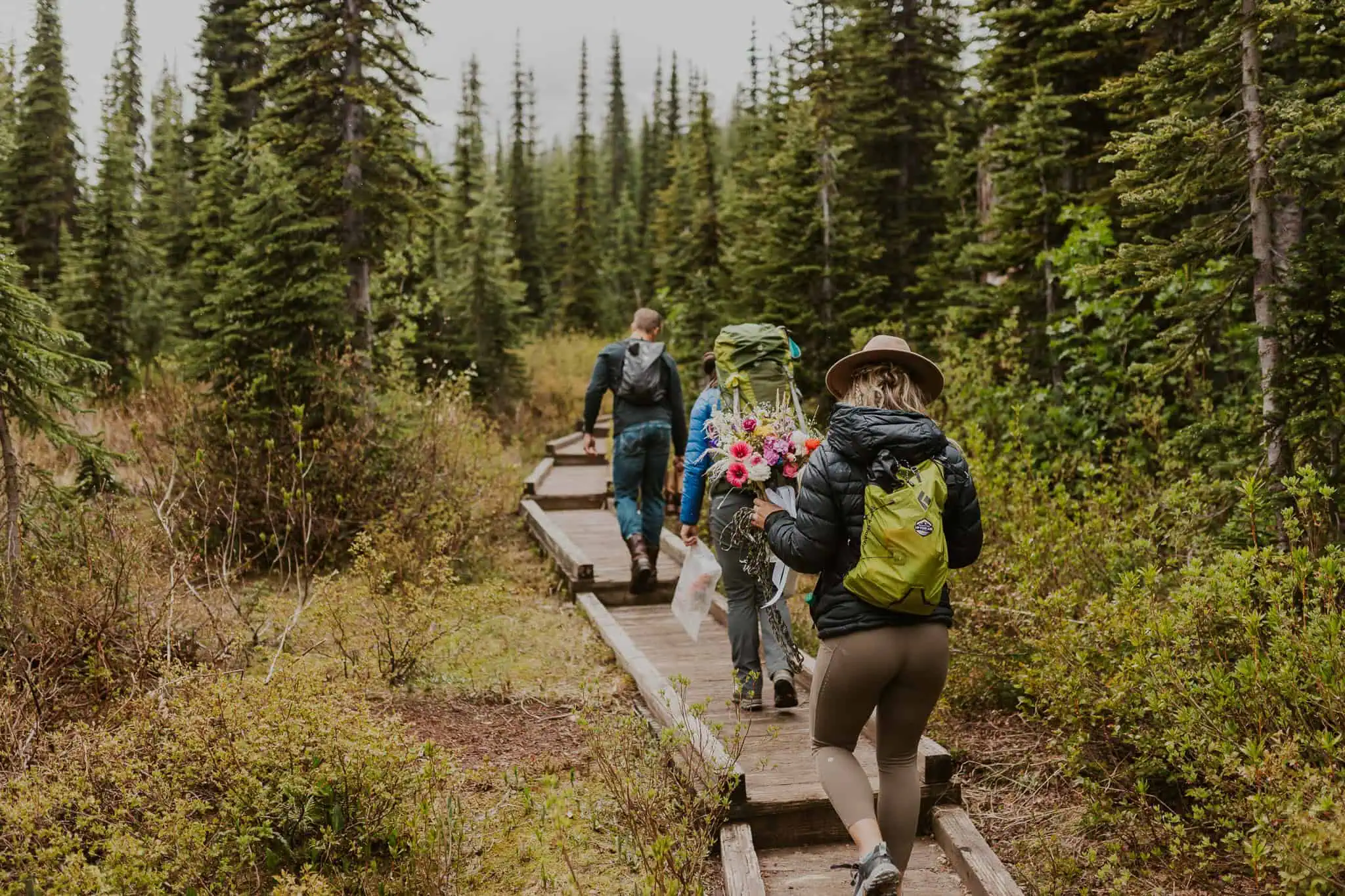 3 people hiking on a wooden boardwalk