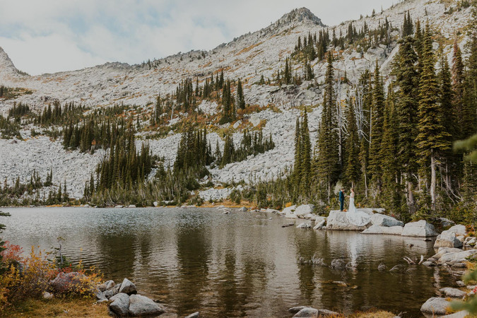 a couple saying their private vows in the mountains by an alpine lake