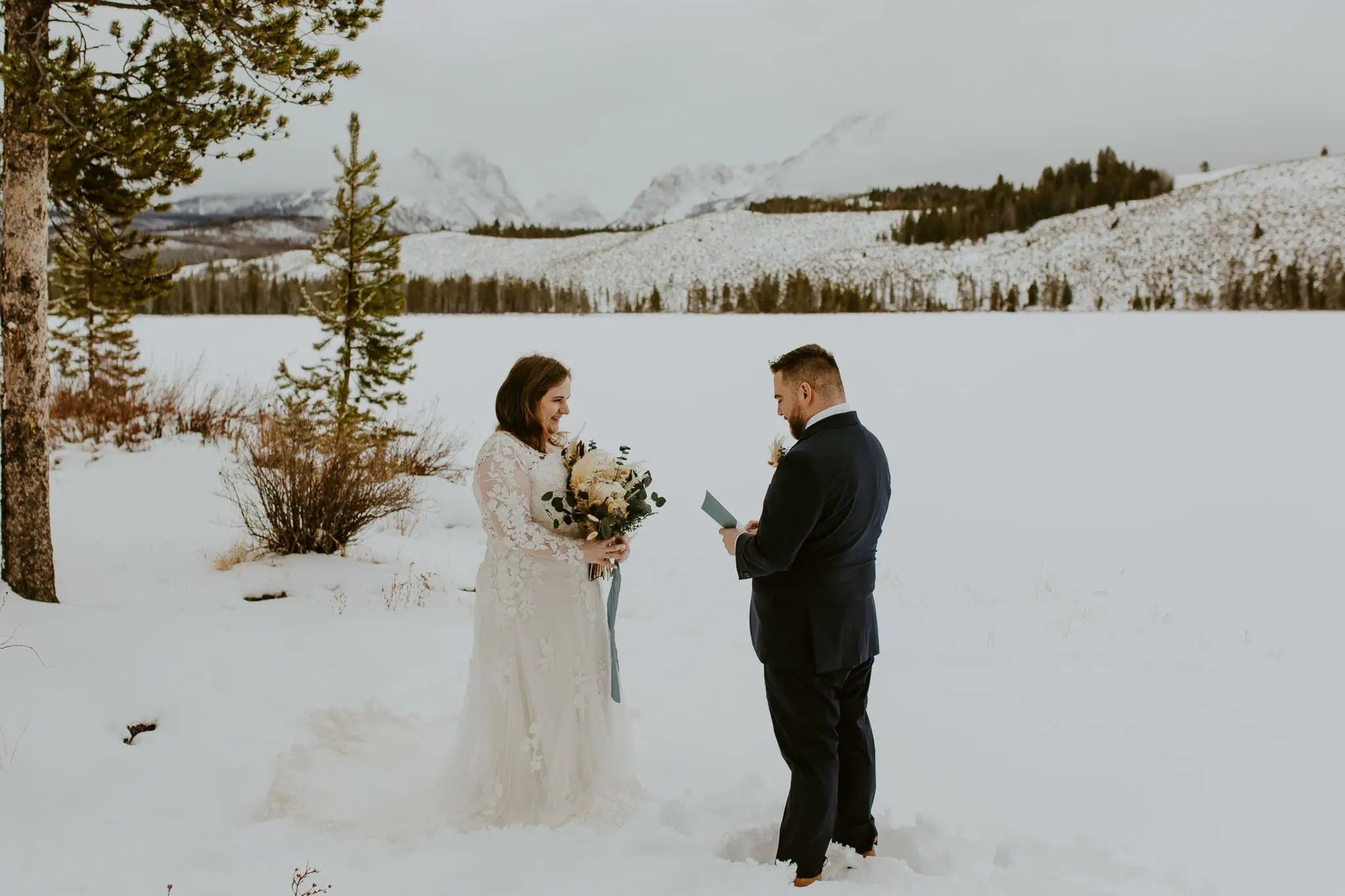 groom reading his vows in front of snowy mountains in idaho