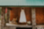 a wedding dress hanging off the porch of a cabin