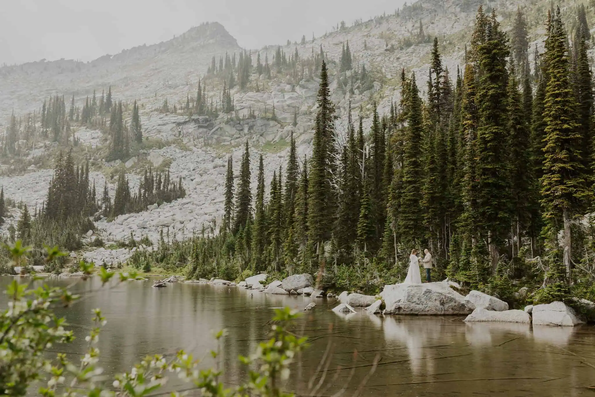 bride and groom reading vows on a rock in the water