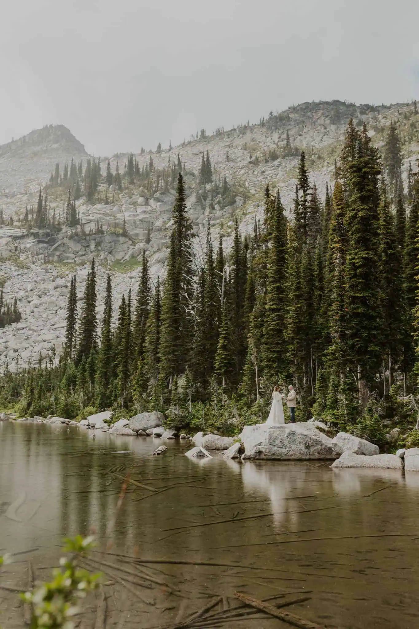 a couple reading vows on a rock in the water for their elopement