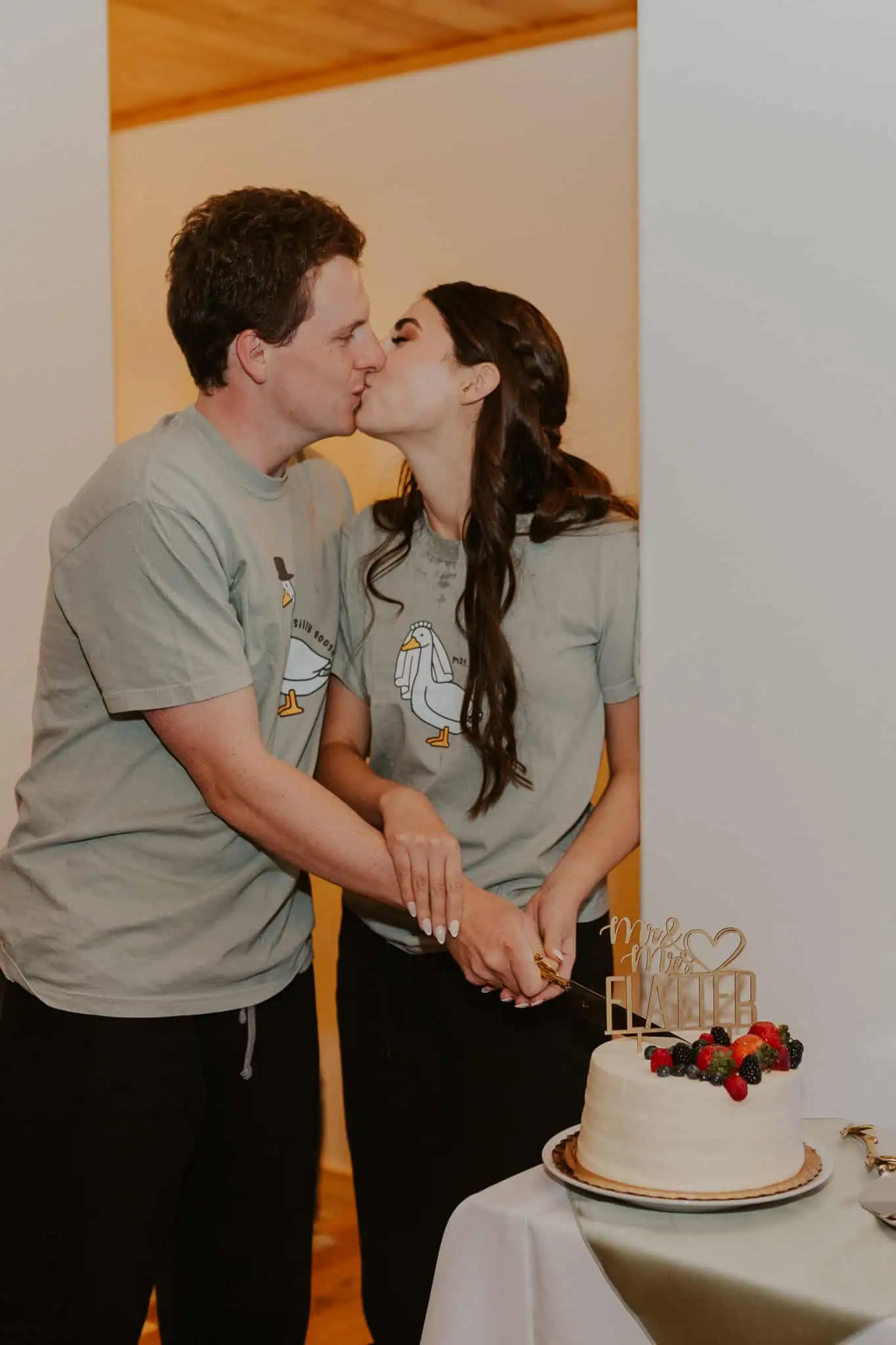 couple wearing matching shirts and cutting cake