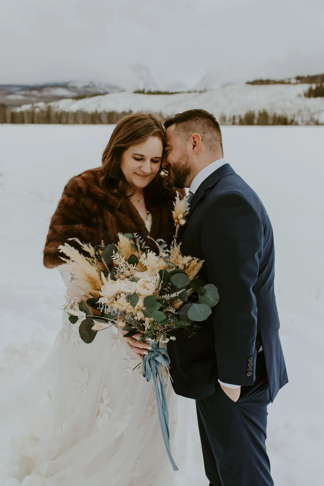 bride and groom holding flowers and putting their heads together