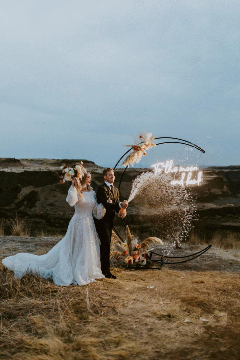 celestial elopement bridals at dusk at palouse falls, washington. Washington adventure bridals, moon arbor, neon sign, sparkly wedding dress, champagne pop. washington elopement photographer