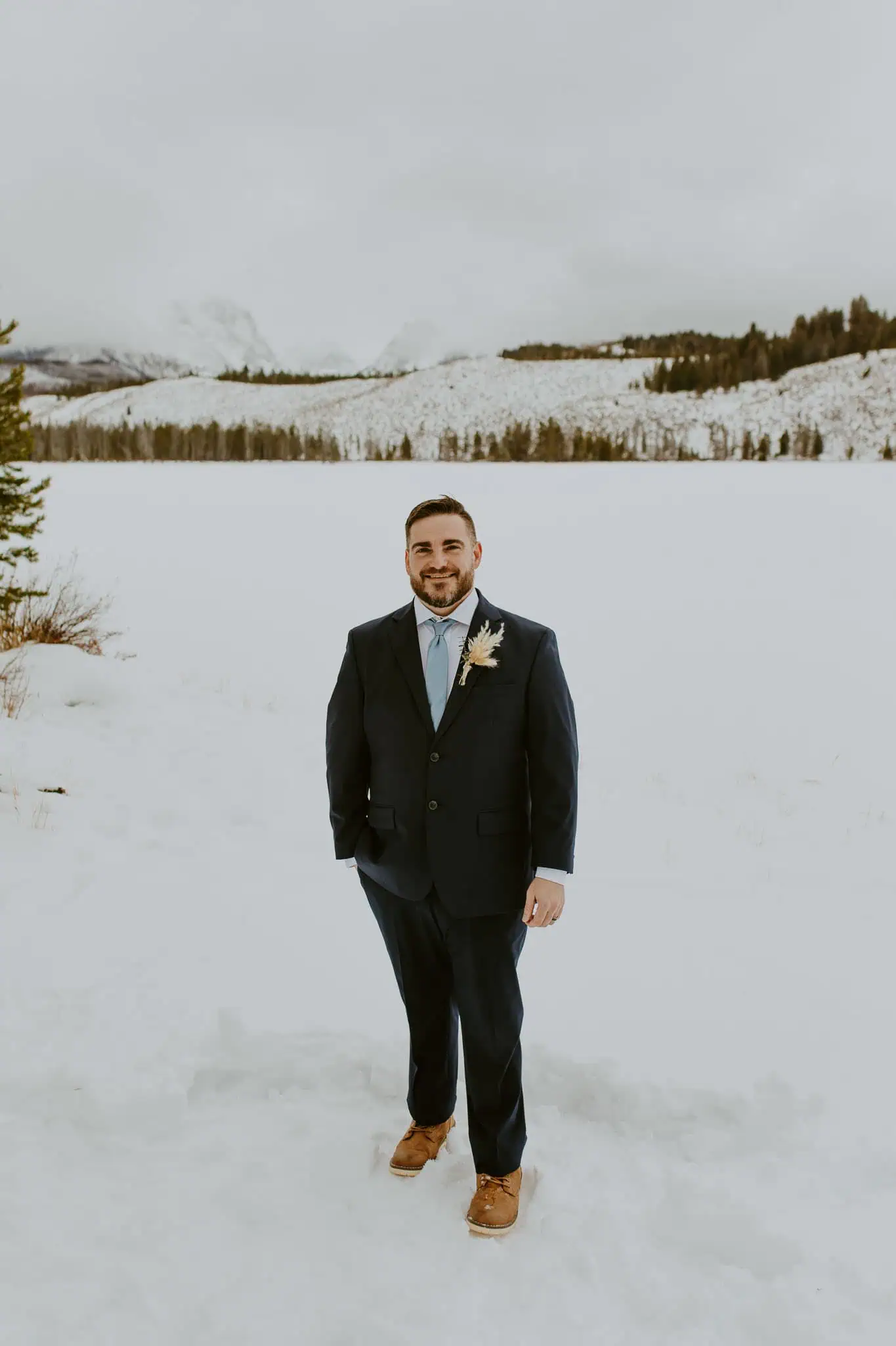a groom portrait in the snow with a blue suit
