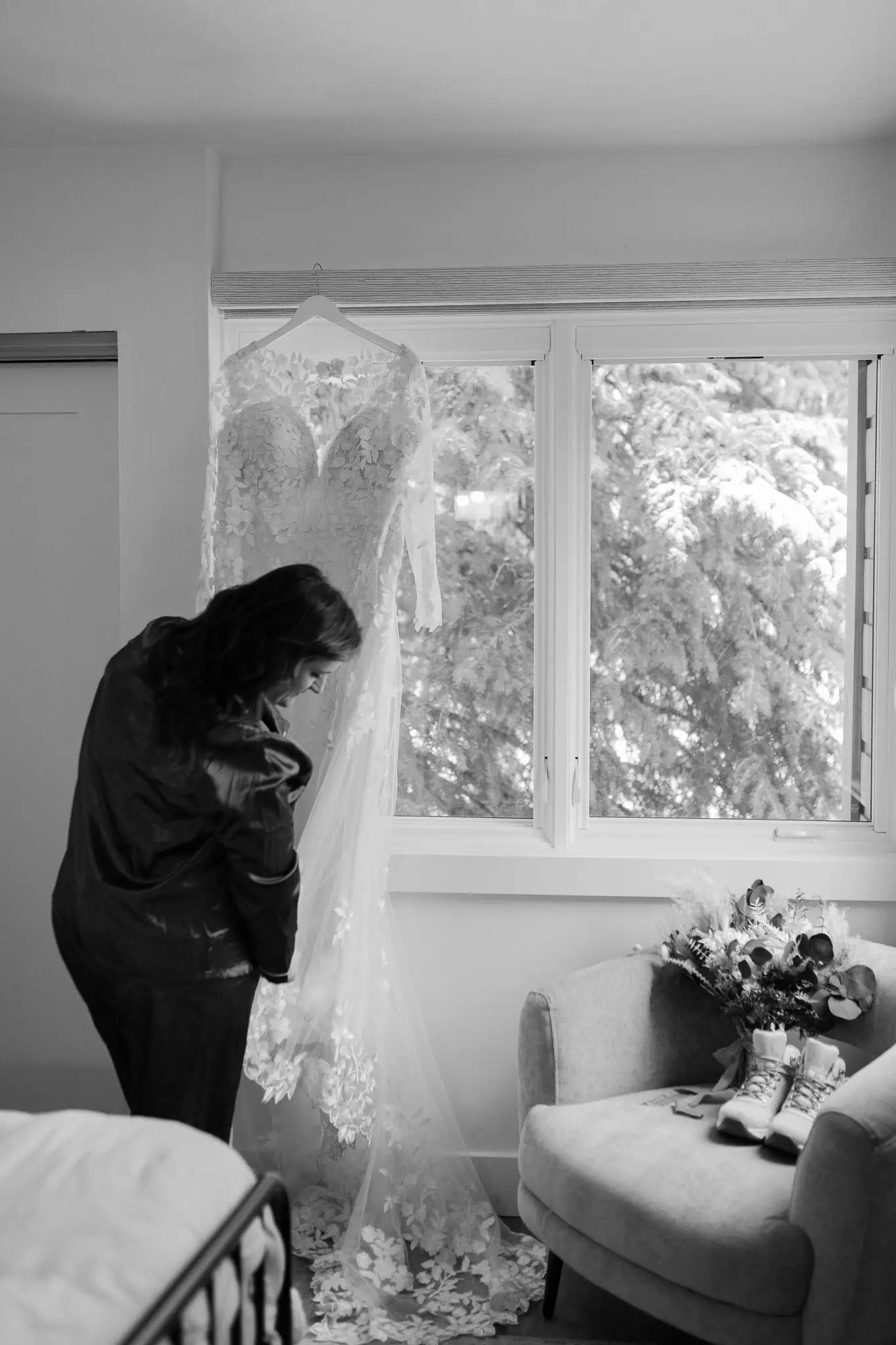 a bride holding the train of her dress as it hangs in the window