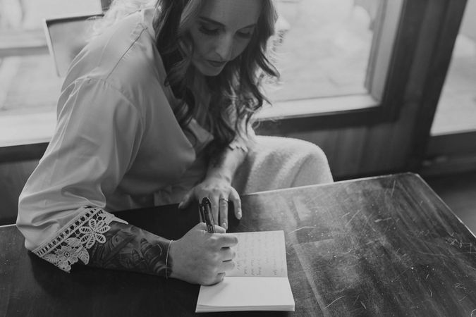 the bride writing her vows in a cabin by a window