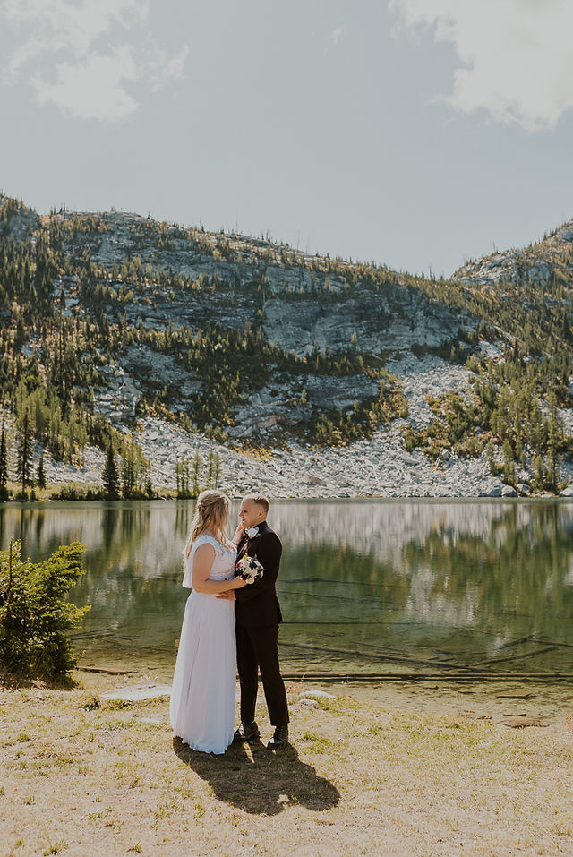 bride and groom doing a first look on the beach of an alpine lake in north idaho