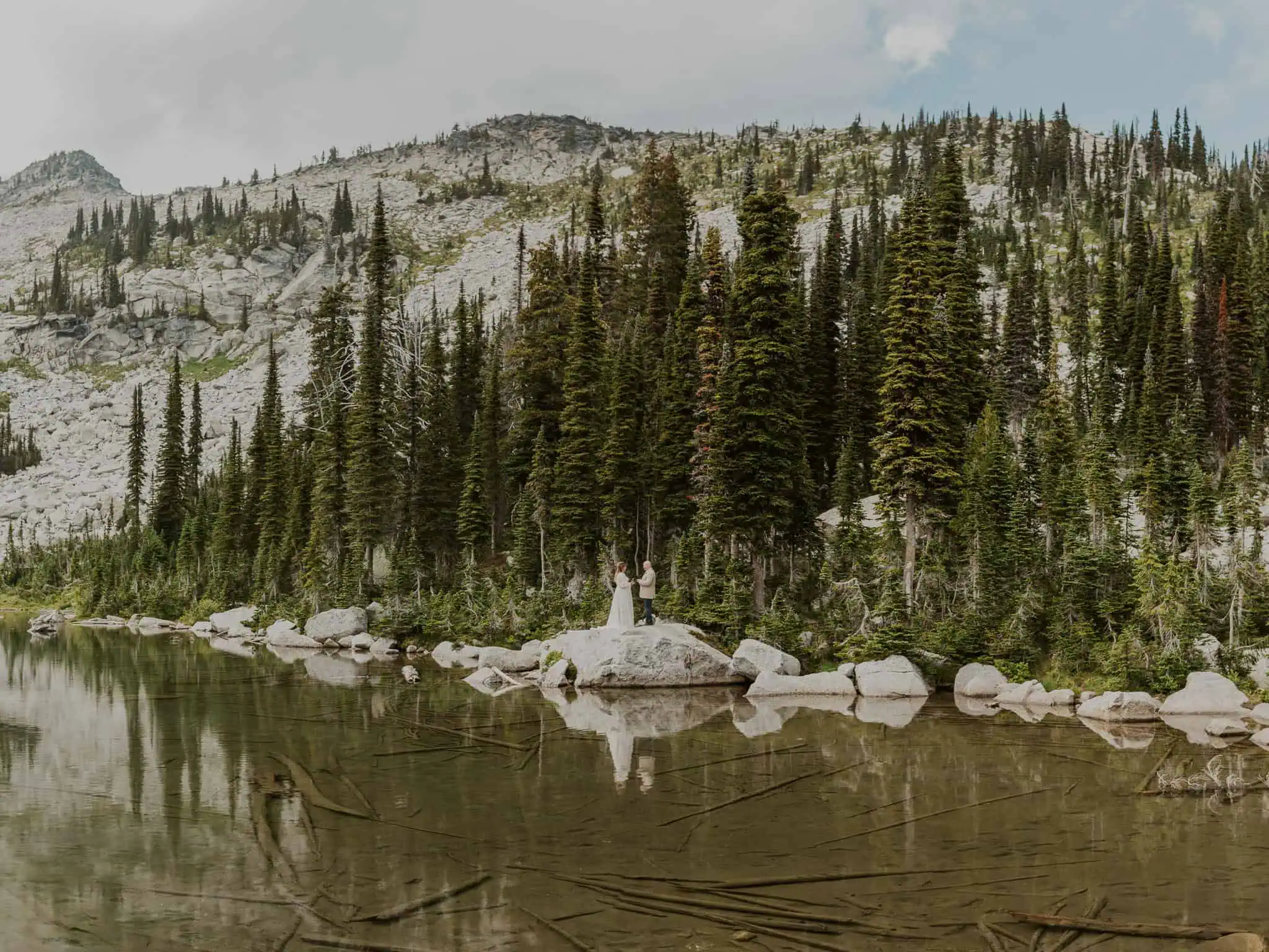 a couple reading vows on a rock in the water for their elopement