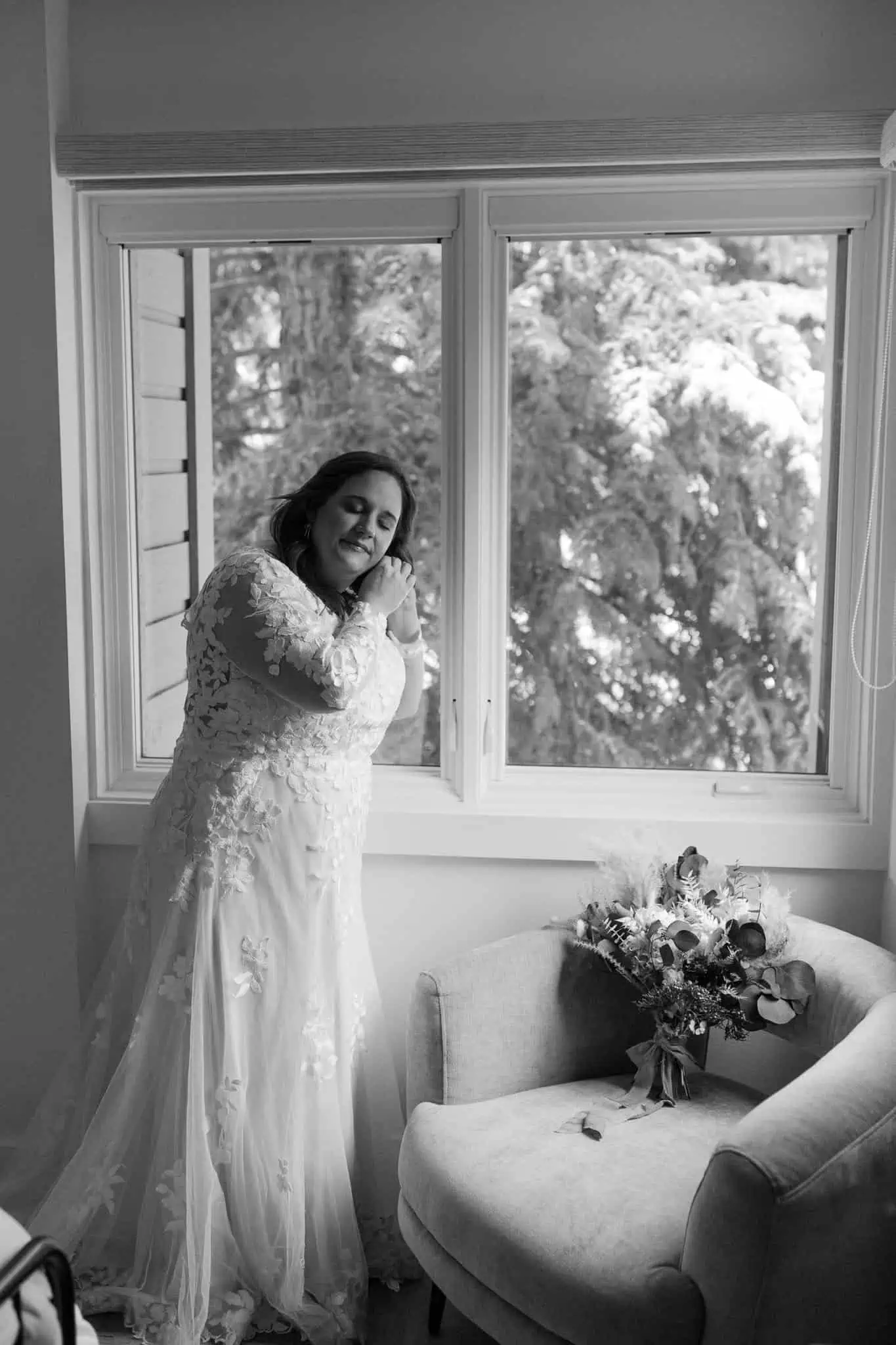 a bride putting on her earrings by the window