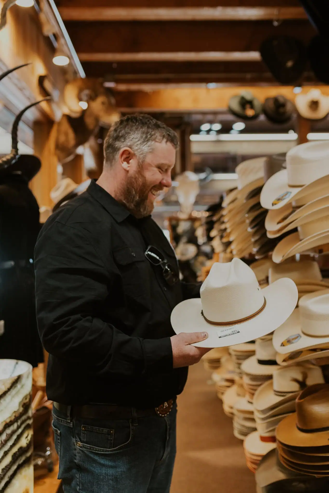 groom picking a hat out at beaver creek hat and leather