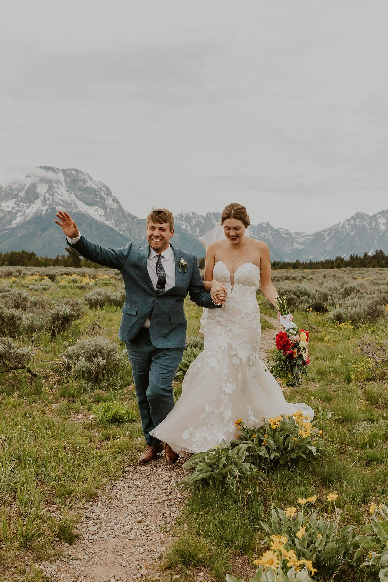 a bride and groom running on a trail in the tetons