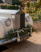 Voiture blanche classique avec des fleurs, plaque d'immatriculation DY-005-SA