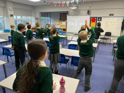 school children stretching in a classroom for an activity